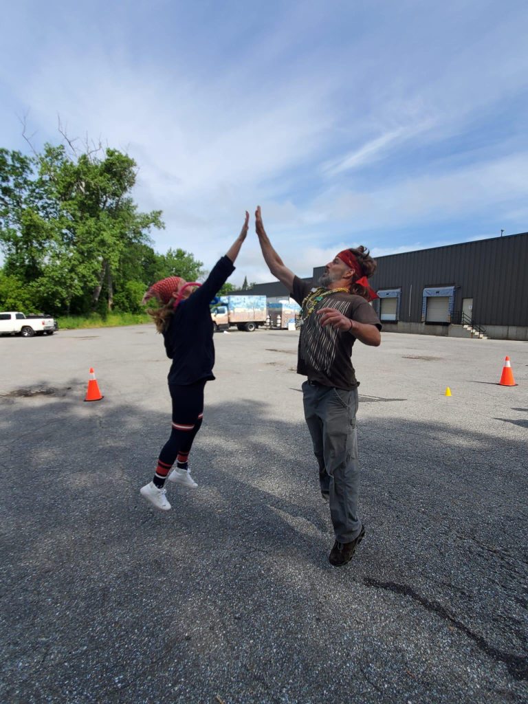 Two children play frisbee with a high jump catch game in an outdoor parking lot.