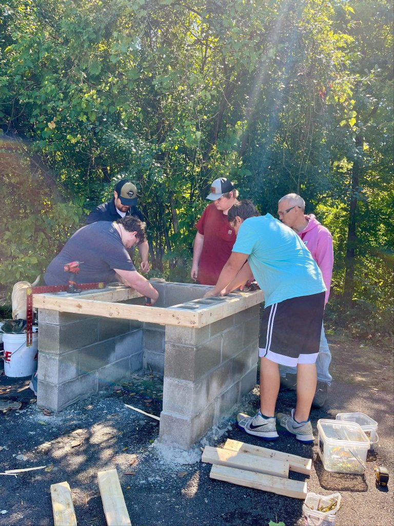 Group of men working with a concrete block structure outdoors.