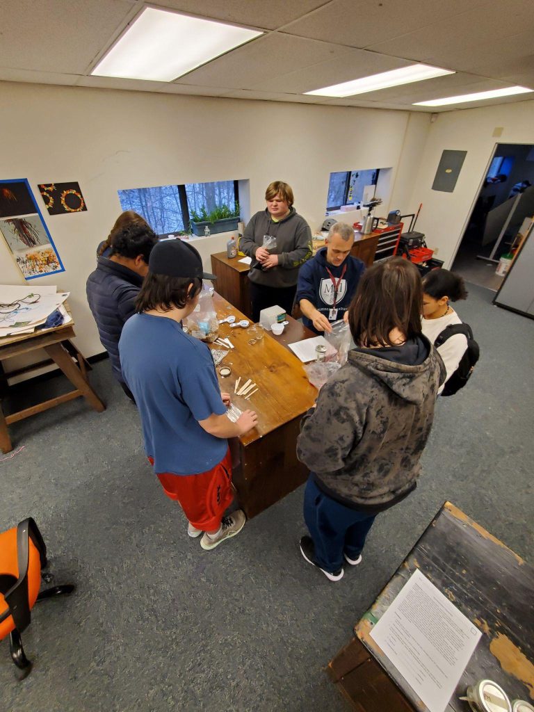 A group of people are gathered around a table with papers and writing instruments at an office space.