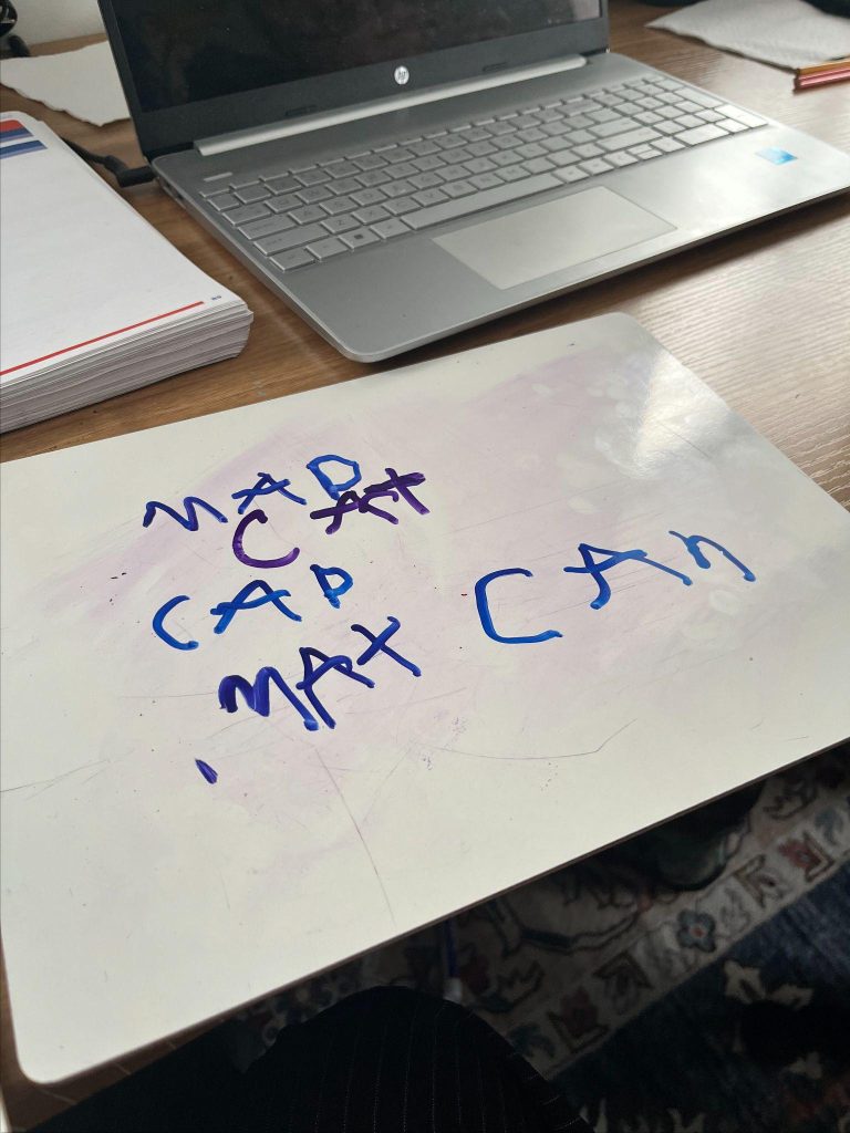 A laptop with a paper that says "MAX CAB" written on it is placed on top of another piece of paper with.