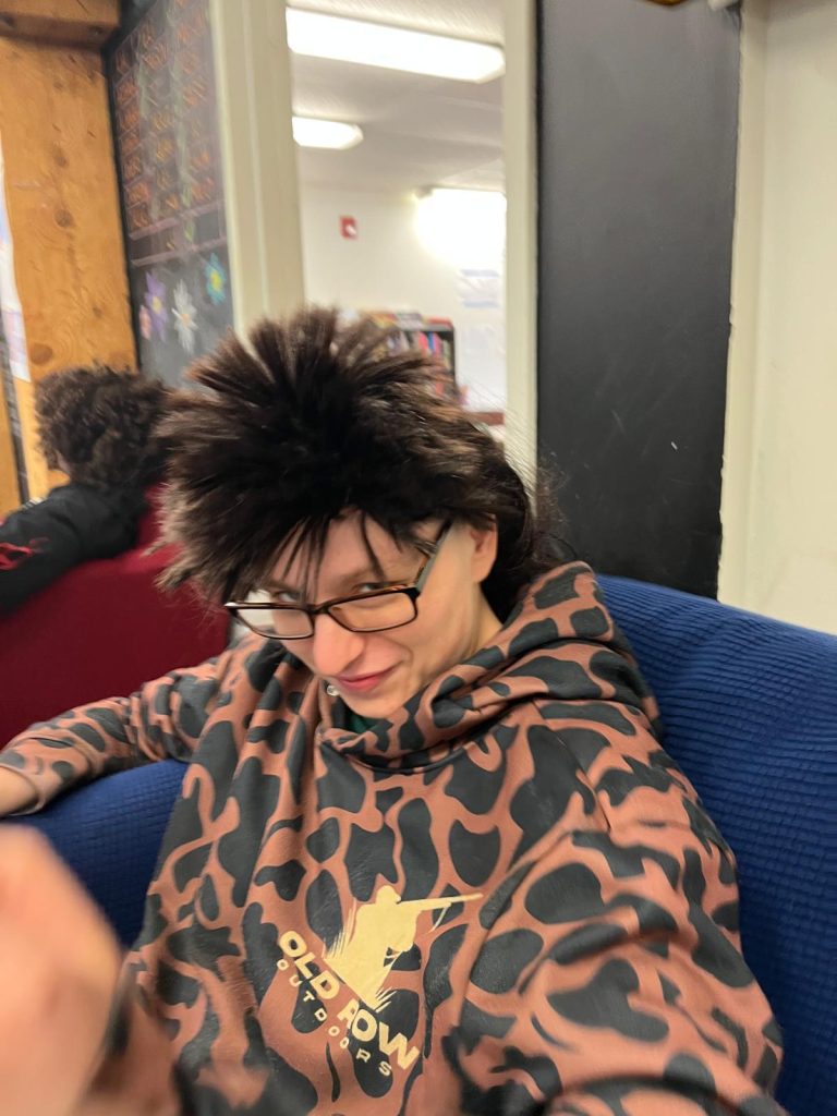 A person with glasses and a hoodie is sitting down.