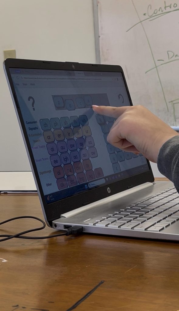 A person is interacting with a laptop screen displaying a game interface.