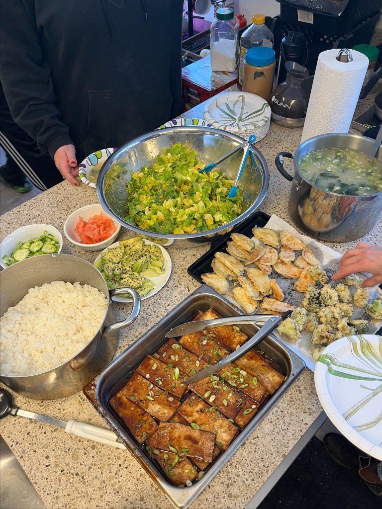 A table filled with various dishes and food items is shown to be covered by a plastic sheet or film.